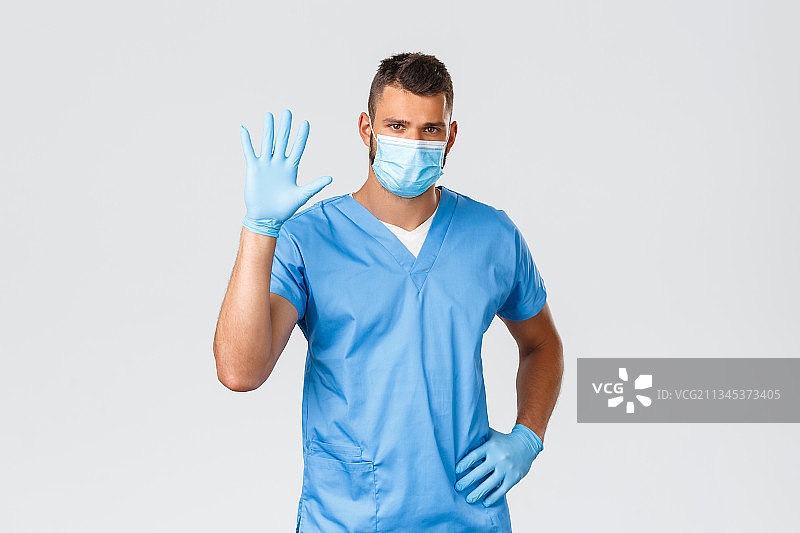 医生的肖像，戴着外科口罩，站在白色背景图片素材