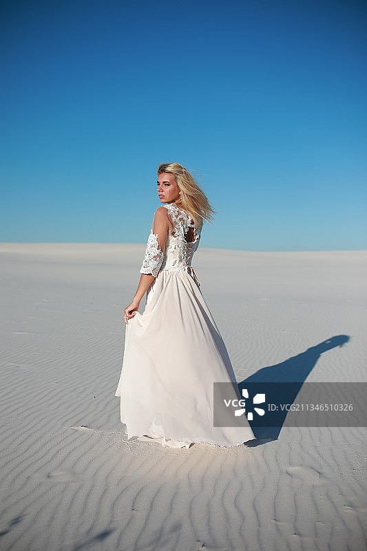 完整的新娘行走在沙滩上，在清澈的蓝天下图片素材