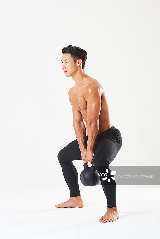 摄影棚拍摄的男子肌肉锻炼与水壶铃在白色背景图片素材