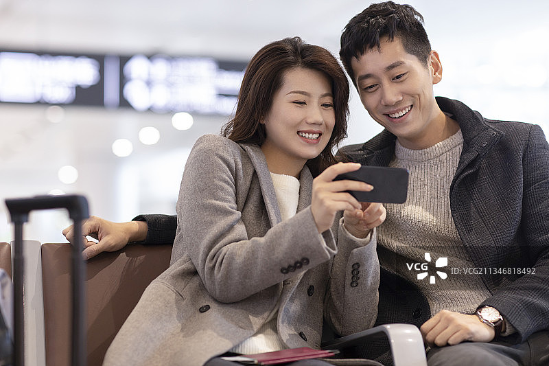 年轻夫妇在机场使用手机图片素材