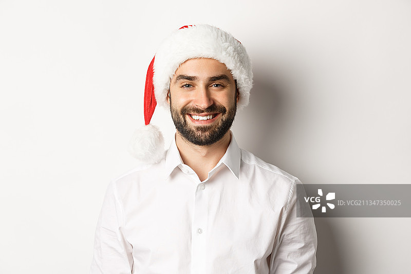 微笑的年轻人的肖像戴着圣诞老人的帽子在白色的背景图片素材