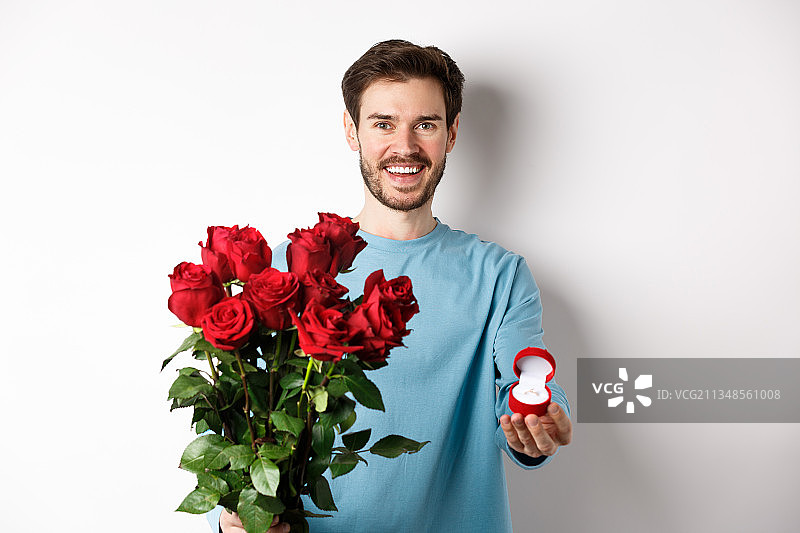 在白色背景下，微笑的男子手持红玫瑰图片素材