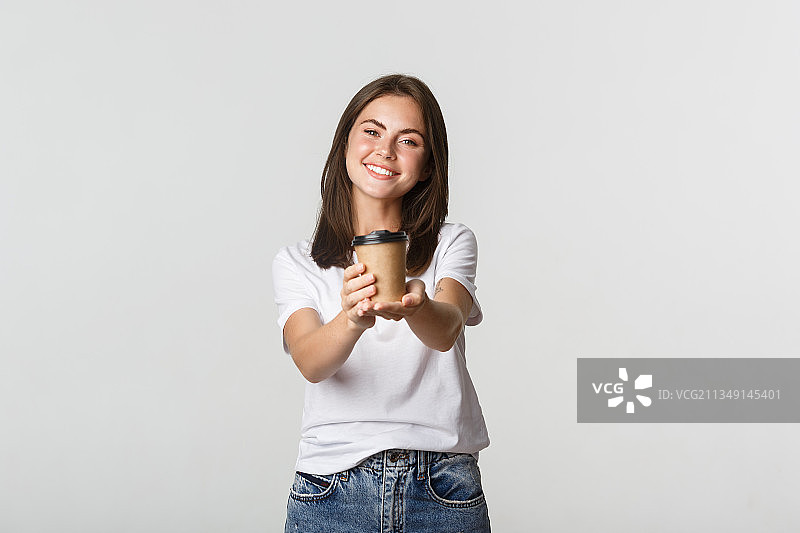 一名微笑的年轻女子手持咖啡杯，站在白色背景下图片素材