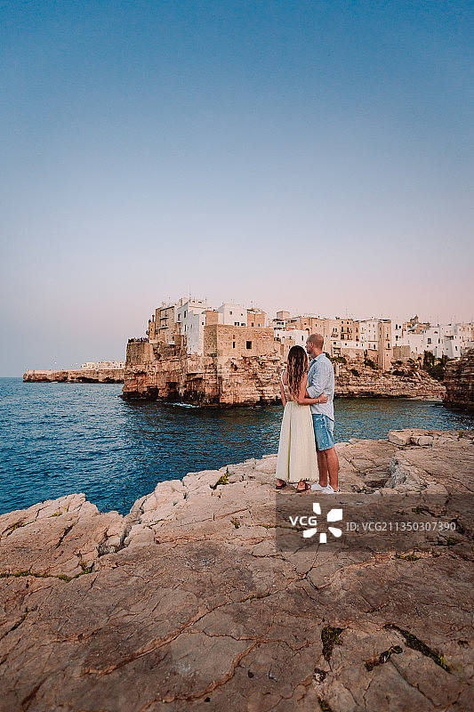意大利Largo Gelso，一对情侣站在海上的岩石上图片素材