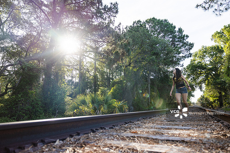 快乐的年轻女人在铁轨上玩，盖恩斯维尔，佛罗里达，美国，美国图片素材