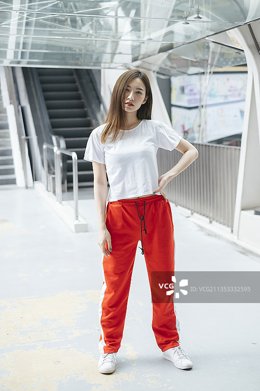 时尚肖像-美丽的亚洲年轻女子在白色衬衫和红色运动裤站着摆姿势。图片素材