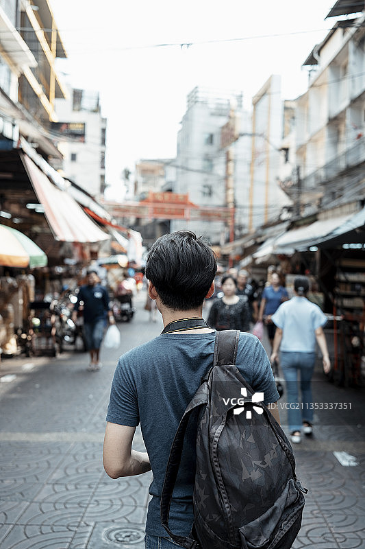 垂直后视图拍摄-年轻英俊的亚洲男子走在曼谷街头市场。图片素材