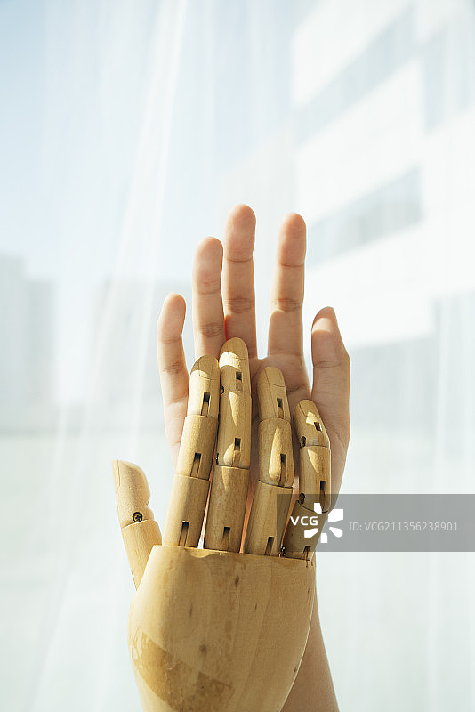 木制半机械人与人的手互相触摸。图片素材