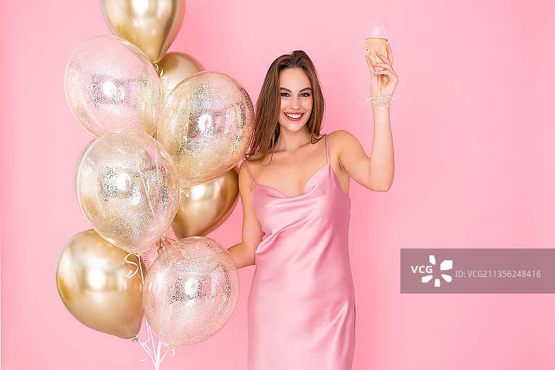 微笑的年轻女子的肖像手持气球对粉红色的背景图片素材