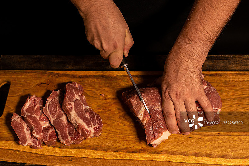 男性的手切肉的特写，切肉的手在砧板上图片素材