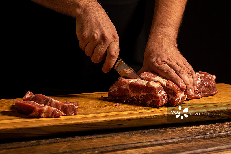 男人的手切肉的特写，男人在砧板上切肉的中段图片素材