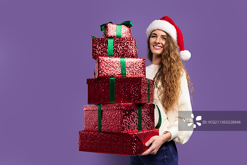 圣诞妇女拿着紫色工作室背景的礼物盒图片素材
