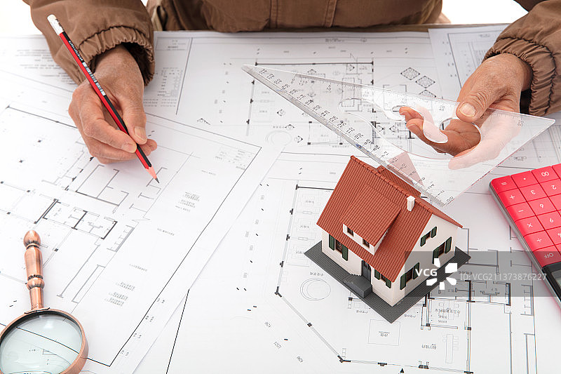 建筑设计师用尺子量着房子模型来分析图纸的精度图片素材