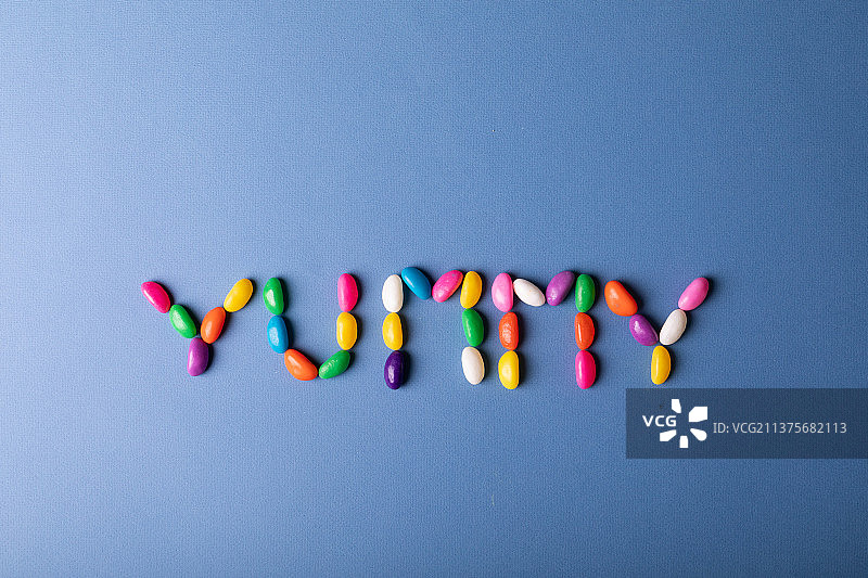 多色糖果的上方视图安排为美味的字在蓝色背景与复制空间图片素材