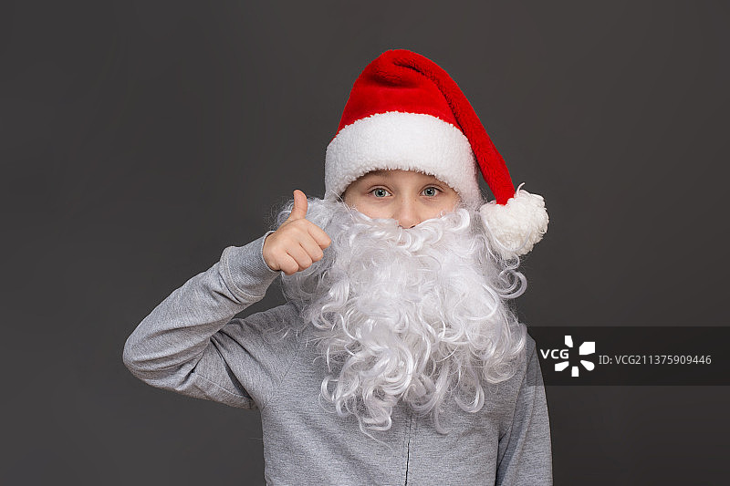 一个留着胡子，戴着圣诞帽的男孩的肖像显示了班级，竖起大拇指图片素材