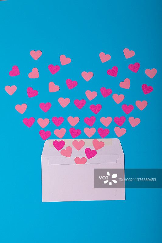 打开白色信封与散在蓝色背景上桃和粉红色的心形图片素材