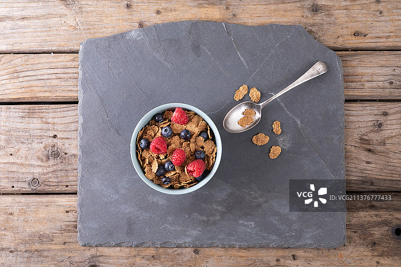头顶拍摄的玉米片、覆盆子和蓝莓，一勺一勺地放在餐桌上的食物板上图片素材