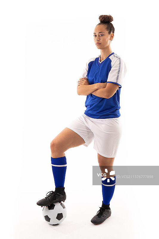 黑白混血的年轻女球员双臂交叉站在足球上的肖像图片素材