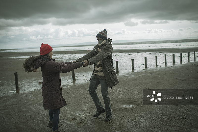快乐好玩的夫妇牵手在冬季海滩图片素材