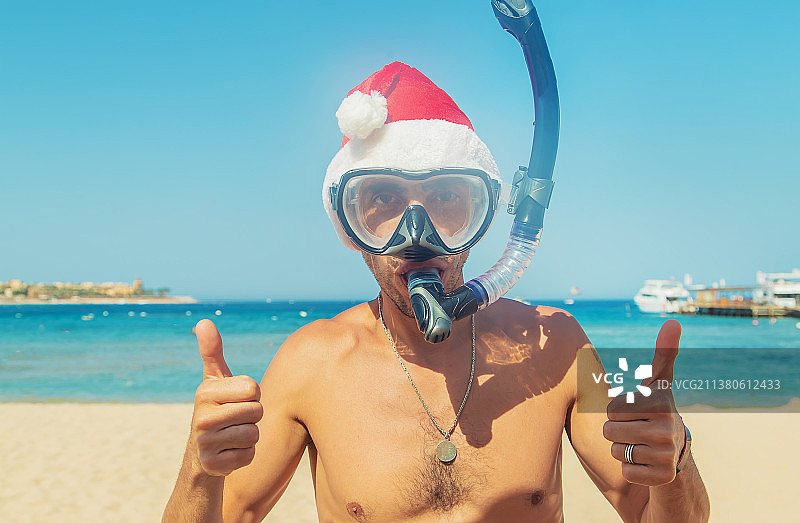 戴着圣诞帽戴着面具和脚蹼的男人在海上选择性聚焦图片素材