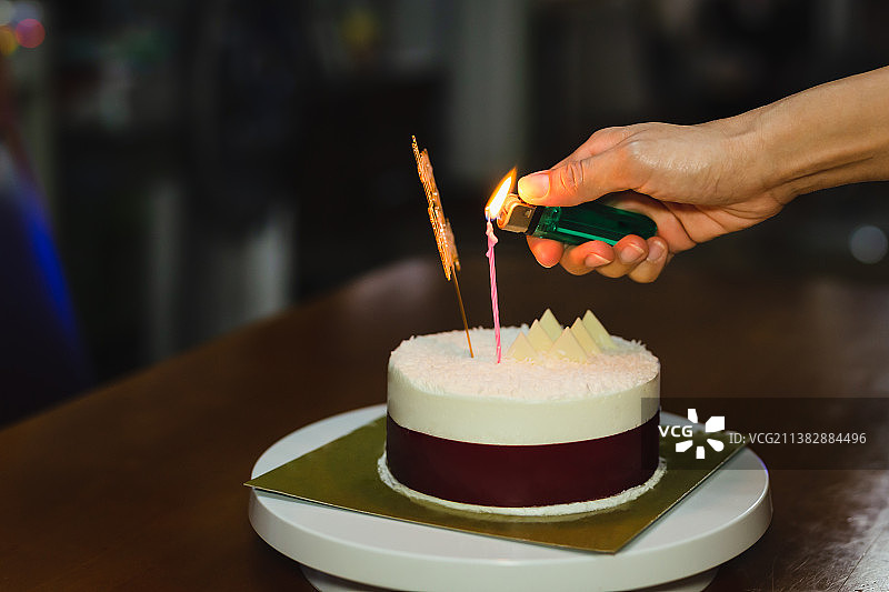 一名妇女在家里点燃生日蛋糕上的蜡烛图片素材