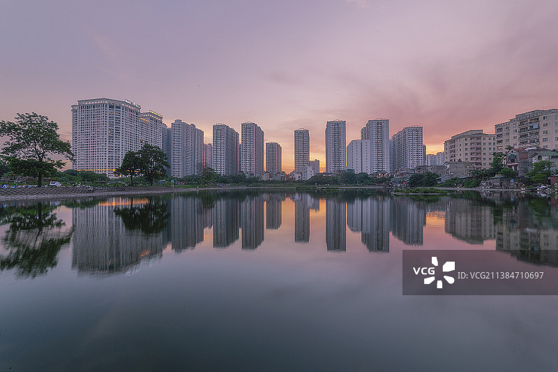 在日落的时候，建筑对着天空的湖的风景，河内，越南图片素材
