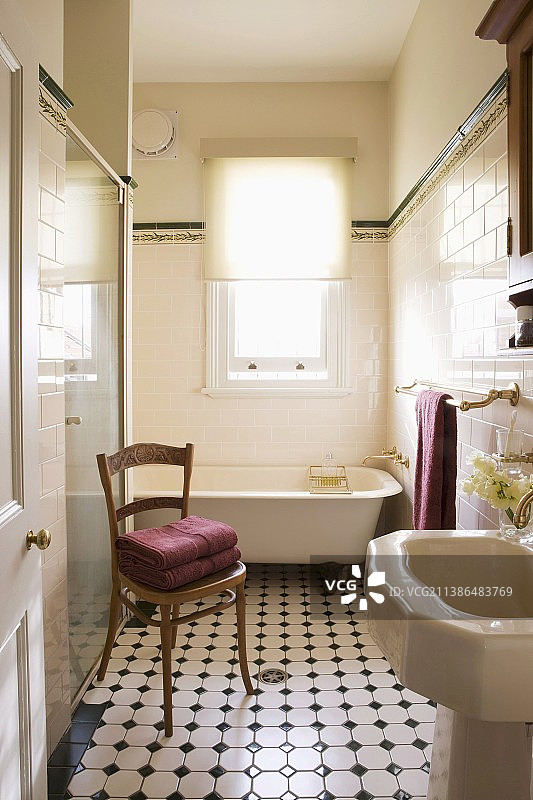 透过敞开的门，可以看到复古浴室里的古董木椅和图案瓷砖地板图片素材