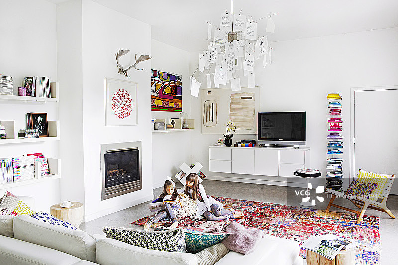 白色的客厅配上五颜六色的配饰，读书的姑娘上了地毯图片素材