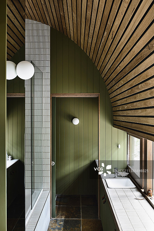狭窄的浴室，绿色的木镶板和弯曲的木制天花板图片素材