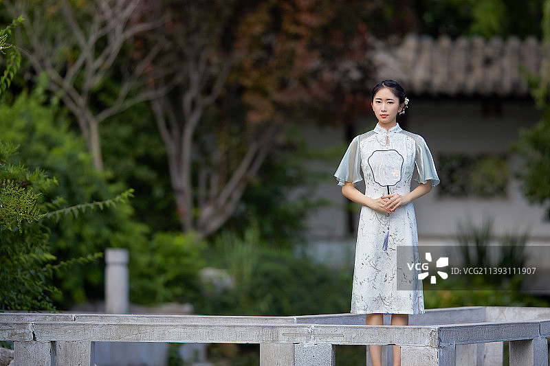 身穿旗袍在庭院里散步的年轻女孩图片素材