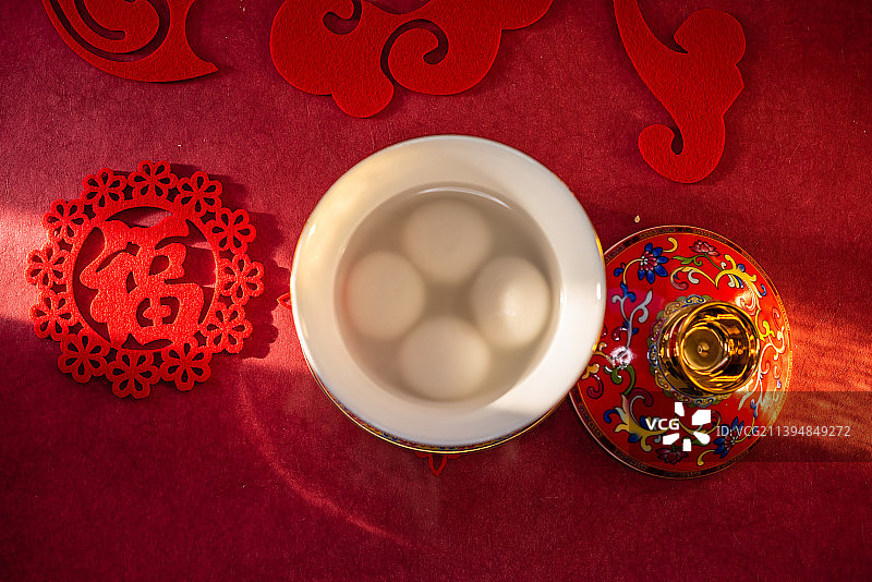 室内棚拍红色中国风背景前的一碗煮熟的元宵图片素材