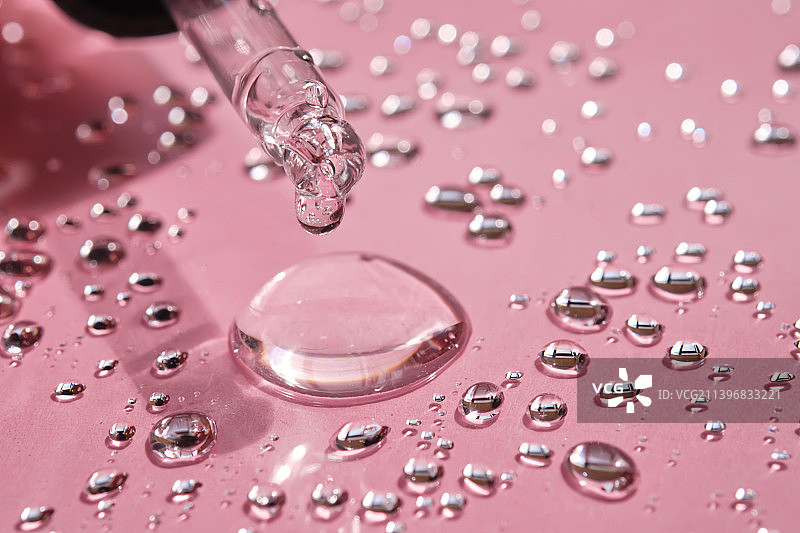 用移液器，将胶束水滴在粉红色的背景上图片素材