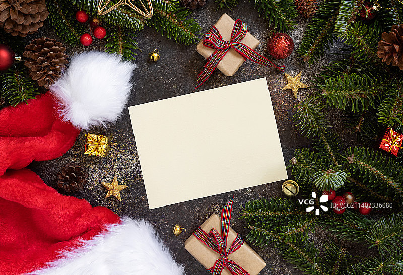 纸卡之间的圣诞装饰，圣诞老人帽子礼盒和绿色的杉树树枝图片素材