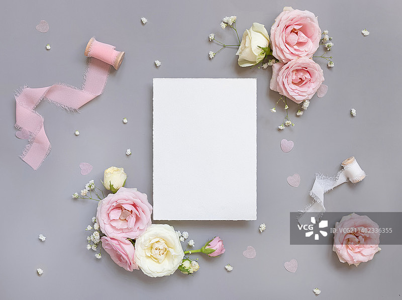 在粉色玫瑰和粉色丝带之间的空白纸卡灰色顶视图，婚礼模型图片素材