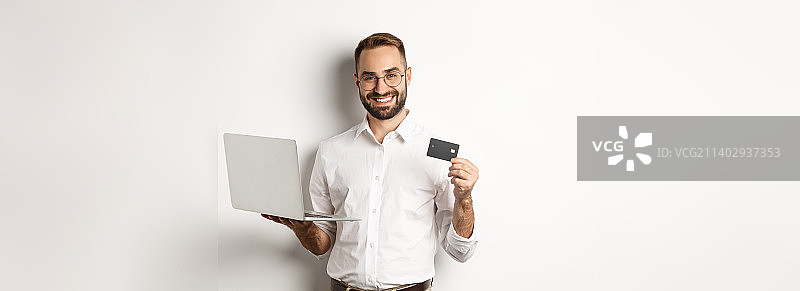 网上购物帅哥出示信用卡，用笔记本电脑图片素材