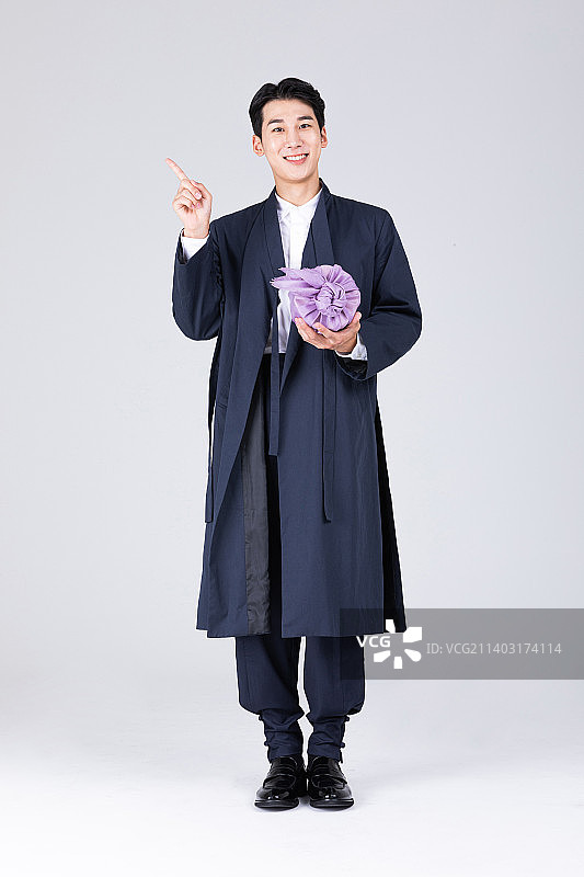 英俊的韩国年轻人，20多岁，穿着现代韩服，穿着韩服，拿着传统的盒子图片素材