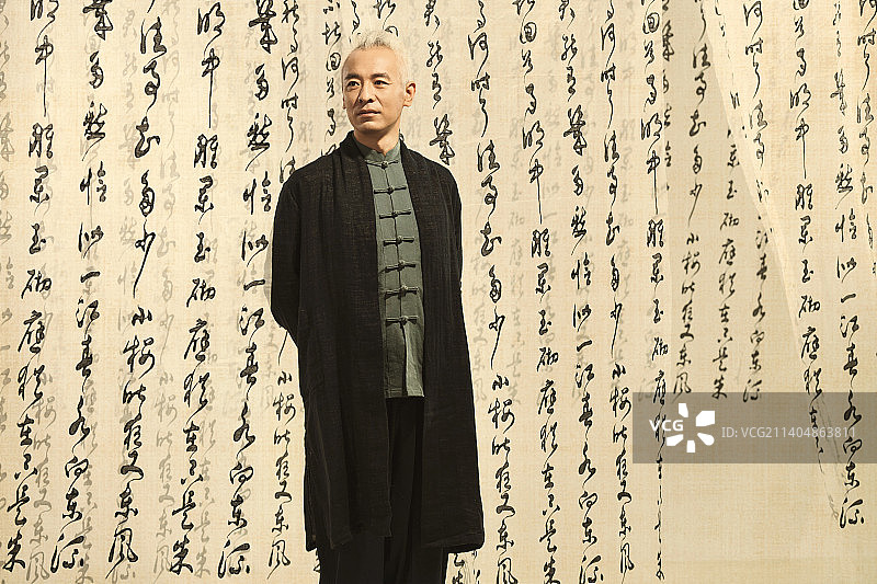 身穿中式服装的男人站在书法前图片素材