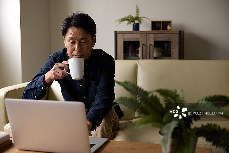 日本男子在家用笔记本电脑工作图片素材