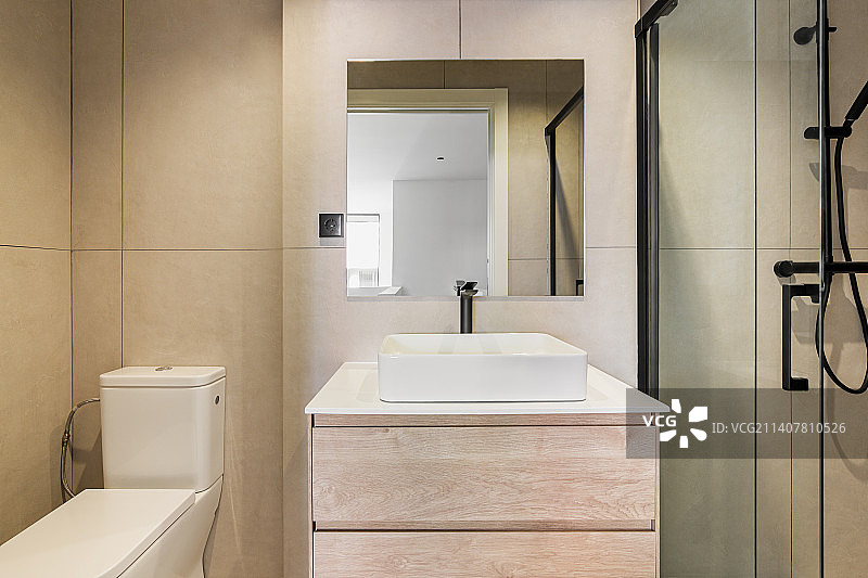 现代化的浴室，米色瓷砖，方形镜子，马桶，白色水槽图片素材