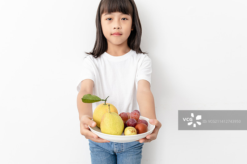 一名中国小女孩手捧着一碟水果图片素材