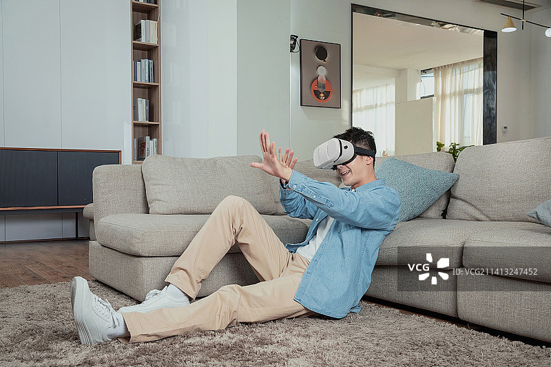 坐在地毯上玩VR的年轻男人图片素材