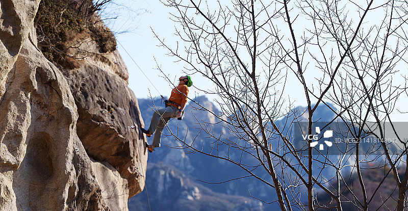 青年男人在悬崖峭壁上攀岩图片素材