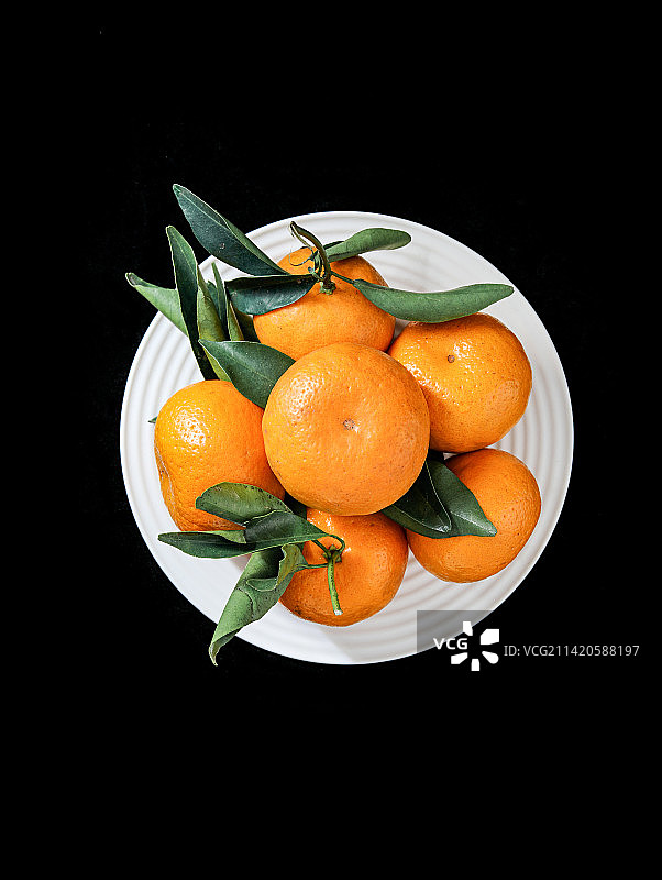 黑色背景上一碟子的新鲜水果橘子图片素材