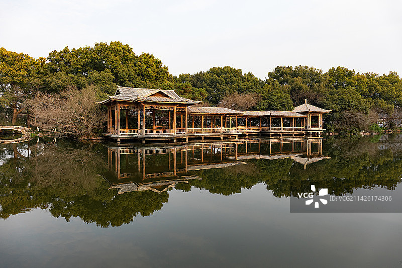 杭州西湖一栋中国风园林建筑与背景的绿色树林在湖中的倒影图片素材