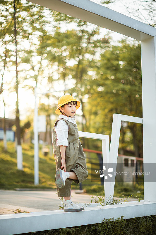 公园里戴小黄帽穿绝色连体裤的可爱小男孩图片素材