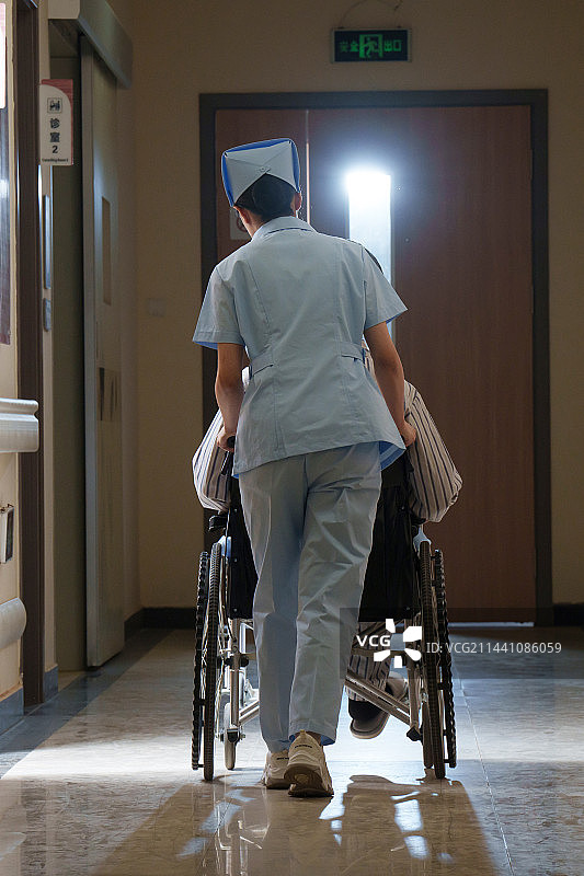 走廊内护士推坐轮椅的老人背影图片素材
