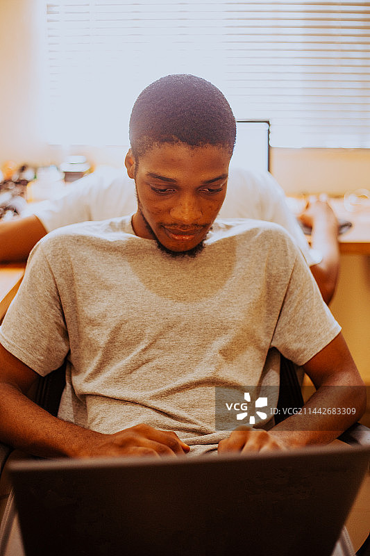 加纳阿克拉，一个年轻人在家里使用笔记本电脑的照片图片素材