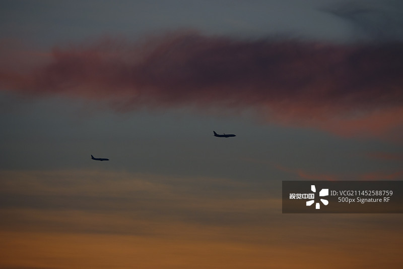 日落时飞机在空中飞行的低角度视图图片素材