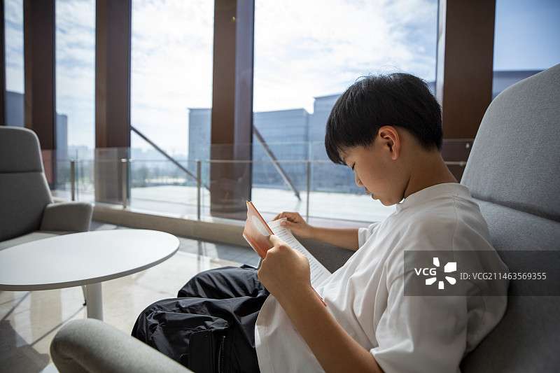 中国小男孩在图书馆大厅看书图片素材