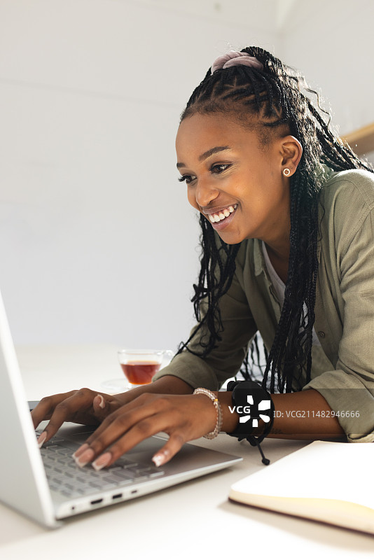 一位年轻的非洲裔美国妇女在使用笔记本电脑时微笑着图片素材